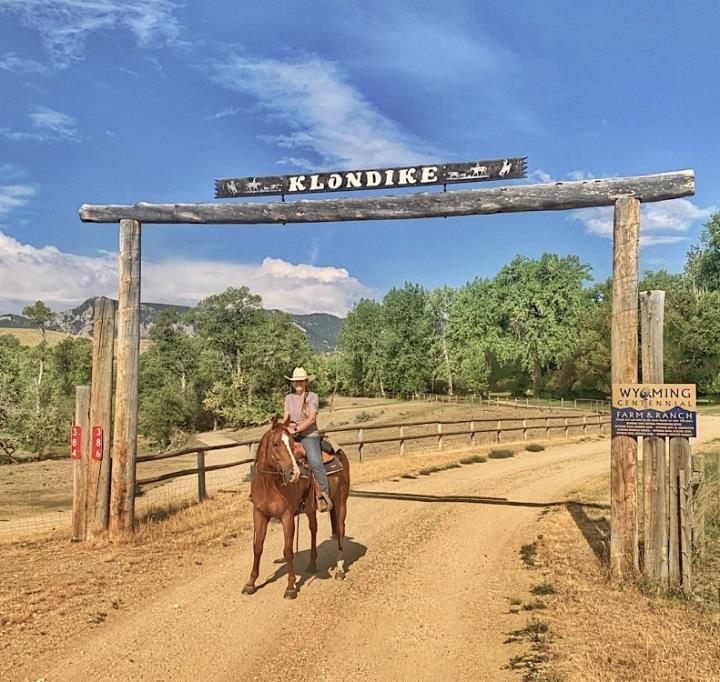 girl wearing western-style hat sitting on stationary horse at the entrance to Klondike Ranch Wyoming