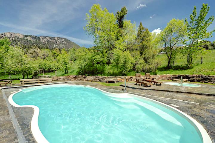 Swimming pool and terrace with loungers surrounded by green bushes